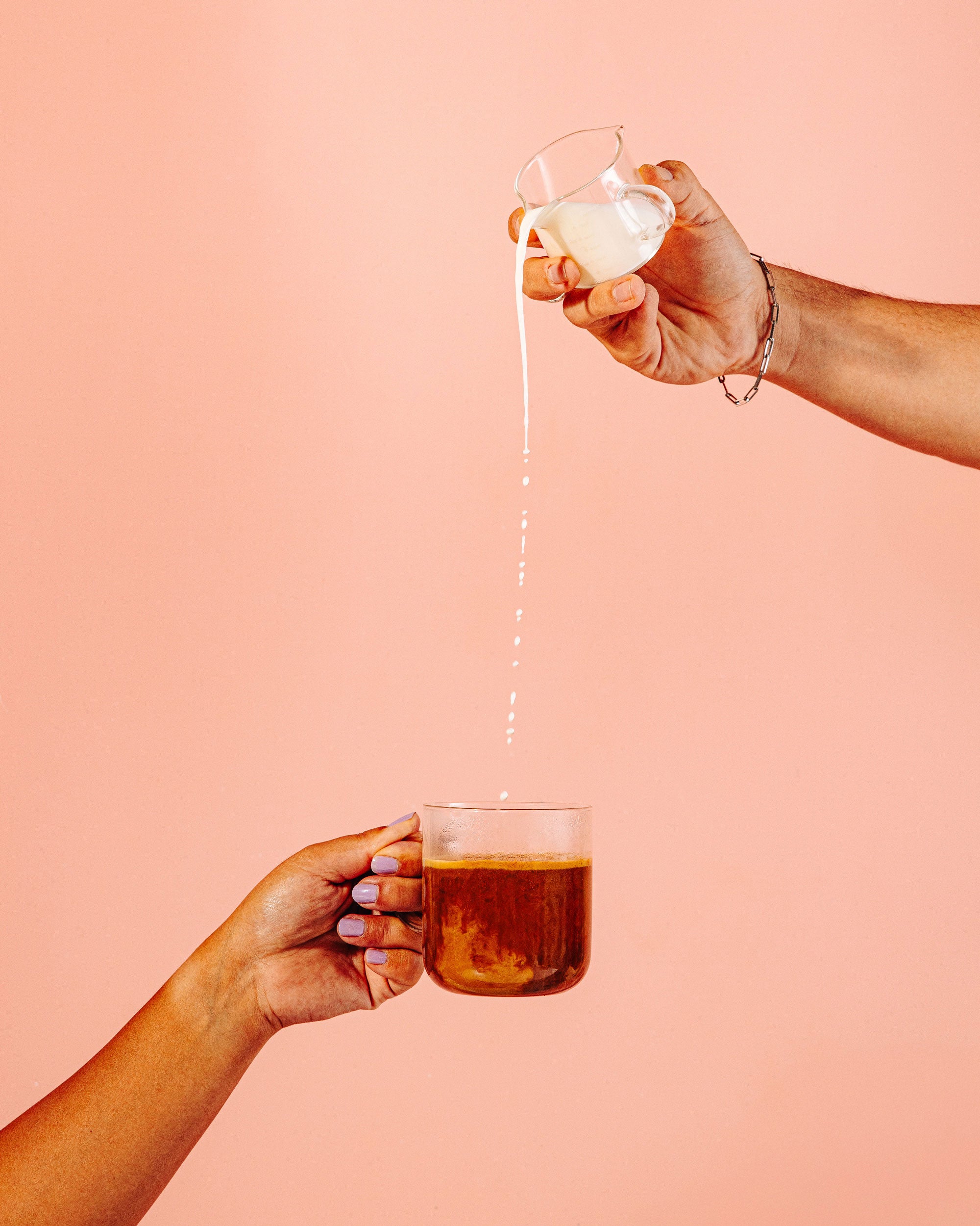 Hand pouring milk into a cup of hot Flowstate coffee from a distance