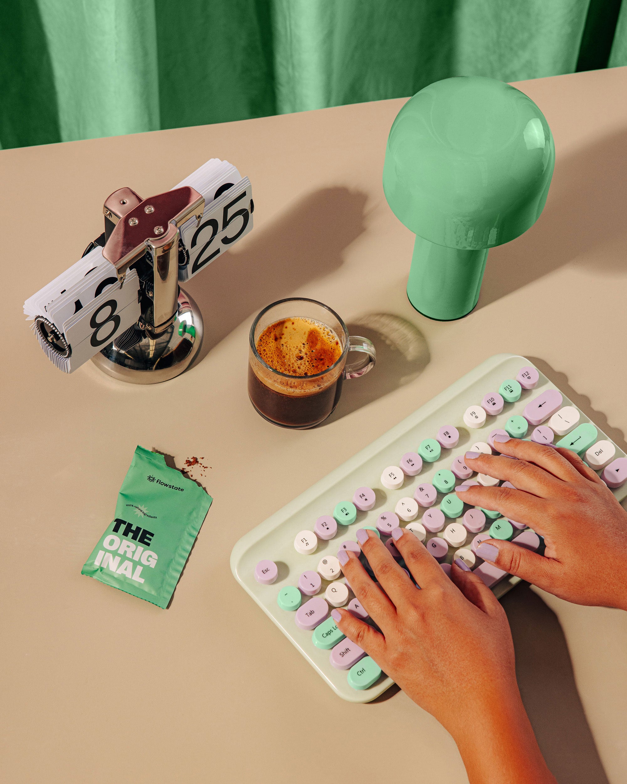 Womans hands typing on a keyboard, with Original Flowstate coffee in a cup